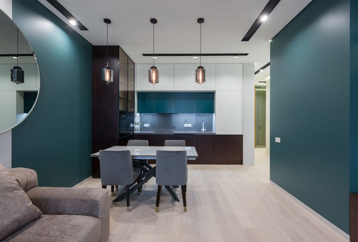 Deep teal wall paired with warm wood furniture and brass accents